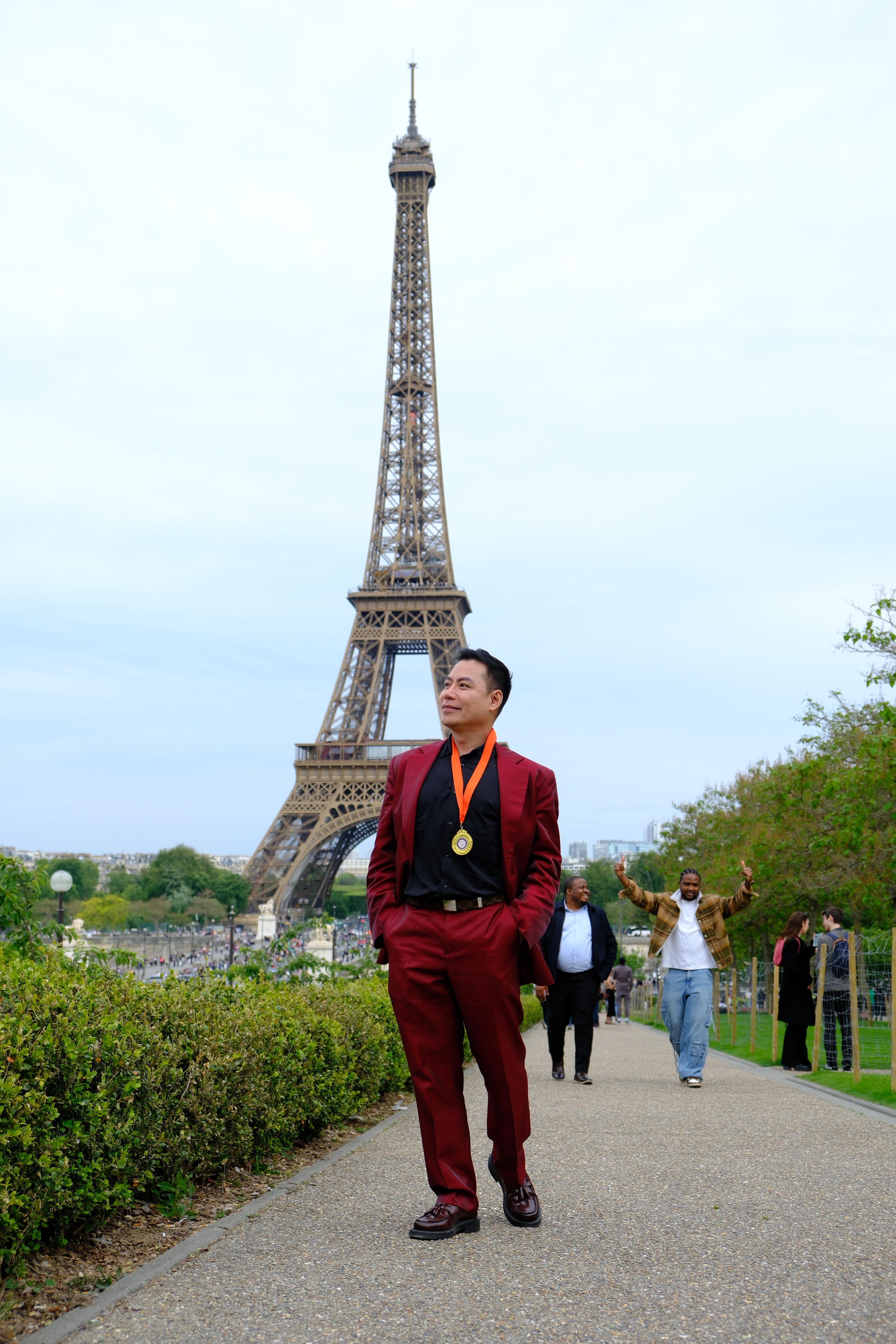 A graduate wearing his medal in front of the Eiffel Tower