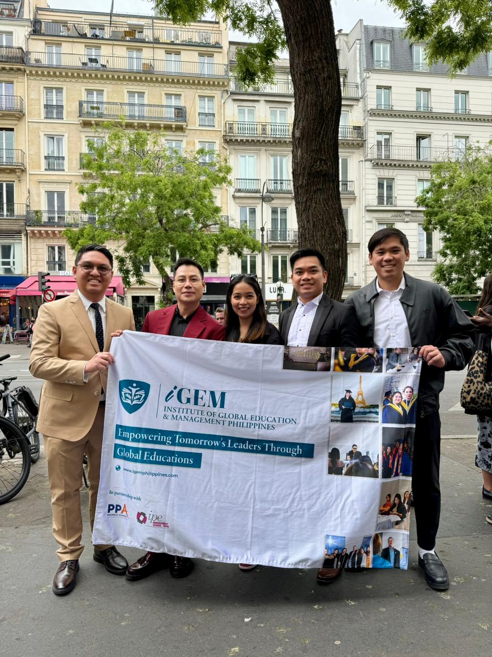 iGEM Philippines graduates holding an iGEM banner on a Paris street after their PPA Business School graduation