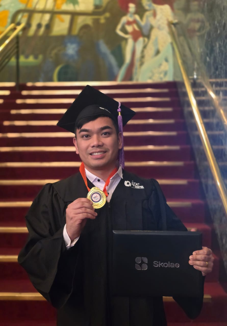 A graduate holding his medal and diploma on the graduation staircase in Paris